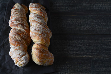 Fresh baguette on a black wooden background.