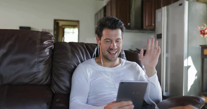 Man Make Online Video Call Using Tablet Computer Sit On Coach In Living Room, Smiling Guy Speaking Internet Communication Slow Motion 60