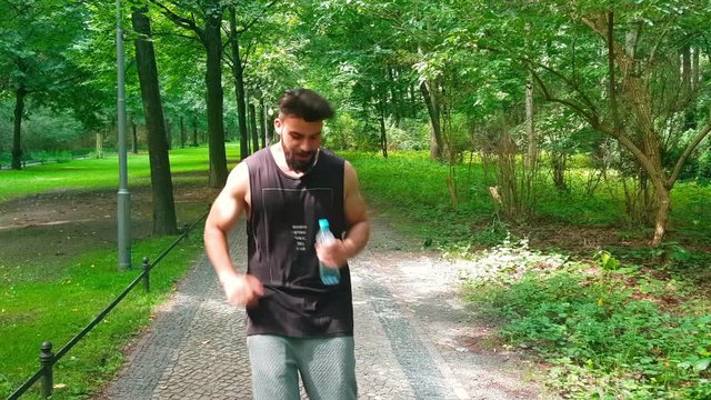 Young man drinking water in the park after jogging