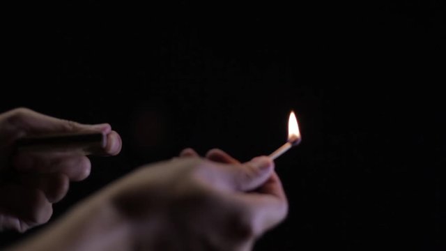 A match being lit and put out in front of a solid black background.