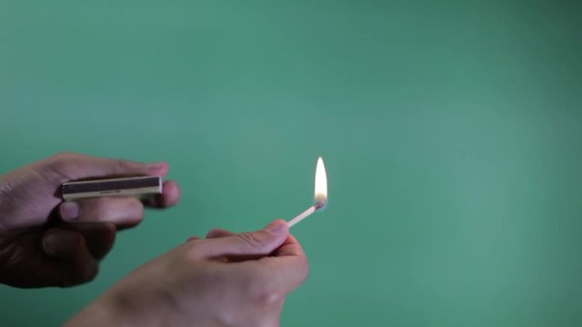 A match being lit and put out in front of a green screen.