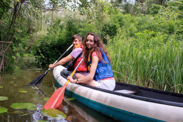 A couple kayaking on a stream in a forest spending their leisure time with fun