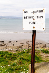 Sign on a beach saying "No camping beyond this point"