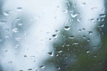 Rain on car windshield during a rainstorm on the road.