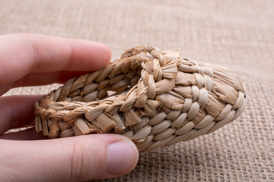 Pair of brown color straw shoes in hand on a brown background