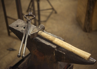 Hammer and tongs on anvil in blacksmith shop
