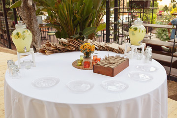 A festive round table setting with a lot of sweets: muffins, lemonade, marsdhmallows and cake....