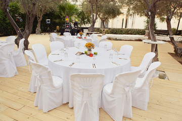 Beautiful white table and chairs in restaurant. Wedding party setting with white draperies