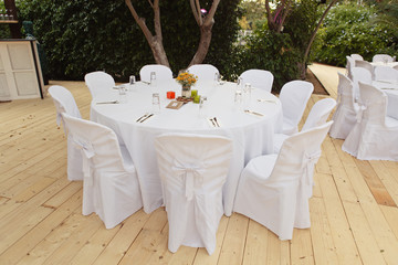 Beautiful white table and chairs in restaurant. Wedding party setting with white draperies