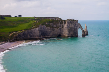 Etretat  chalk cliffs, including three natural arches and a pointed formation called L'Aiguille or the Needle.  Seine-Maritime department, Normandie, in north-western France. April 16th, 2017