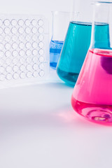 research, science and clinic background. 96 well micro plate and  laboratory beakers with colorful liquids and reagents.