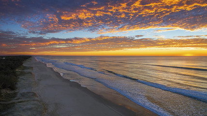 Aerial view of colourful sunrise through a cloudy sky, on Gold Coast beach.