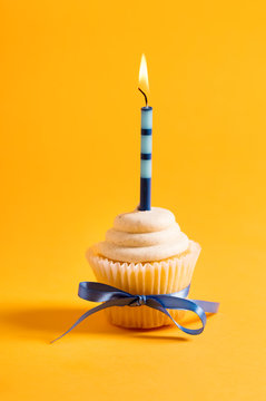 Cupcake with candle celebration theme on a yellow background