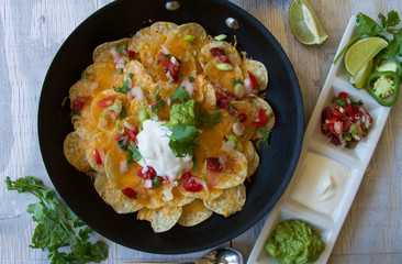 Nachos with chopped tomatoes, onion, jalapeno pepper and melted cheese. Topped with sour cream and guacamole.