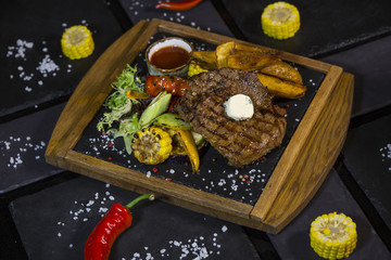 Naklejka na ściany i meble Steak with vegetables. Medium roast meat steak from pork, beef on the board