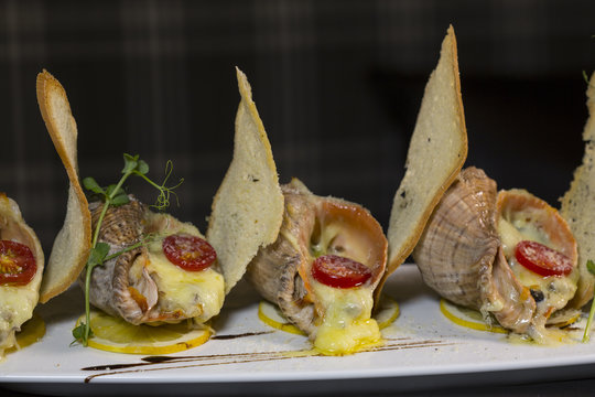 Rape baked with cheese, cherry tomato. Shellfish baked in shell. Rapane.