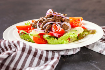 Vegetable meat salad in a plate against a dark background. Selective focus. Copy space