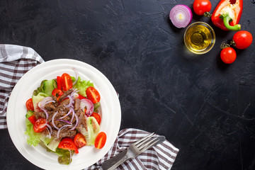 Vegetable meat salad in a plate against a dark background. Selective focus. Top view. Copy space