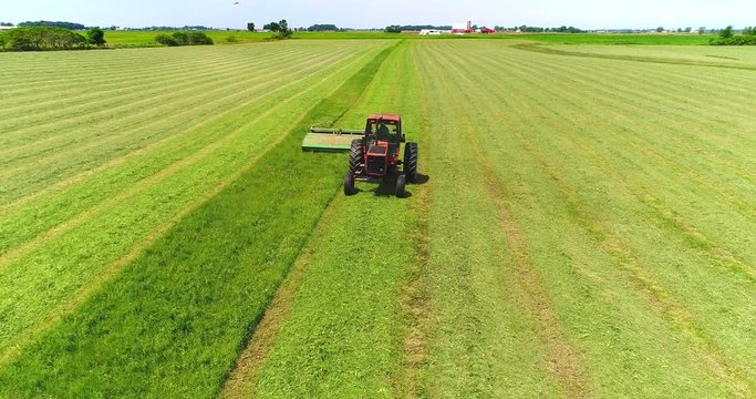 Tractor harvesting crop in field, working fast, aerial view.
