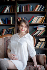 Portrait of a young pregnant woman in white shirt in photo Studio