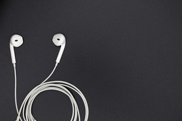Top view of White Earphones on Black background. Copy space