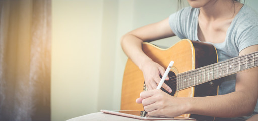 Female musicians play guitar and write songs using the tablet.This image is blurred and soft focus.