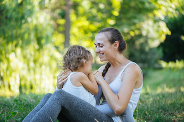 Fototapeta premium Mother and her little girl on green summer grass meadow having fun