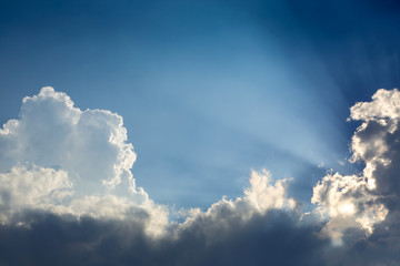 sun rays through cloud above clear blue sky