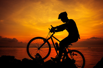 Obraz premium Healthy lifestyle. Silhouette of bicyclist riding the bike at seaside. Outdoors.