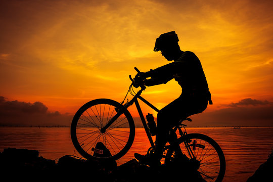 Healthy lifestyle. Silhouette of bicyclist riding the bike at seaside. Outdoors.