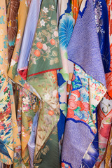 Vertical rack of colorful vintage silk kimonos. Each has a unique pattern. 