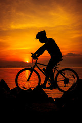 Obraz premium Healthy lifestyle. Silhouette of bicyclist riding the bike at seaside. Outdoors.