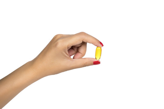 Vitamin, supplement for healthy concept. Closeup of woman hand holding yellow fish oil pill isolated on white background. Healthy eating diet nutrition. High resolution image with space for your text.