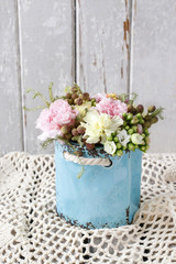 Bouquet of pink carnations and yellow Kalanchoe blossfeldiana flowers in blue ceramic vase.