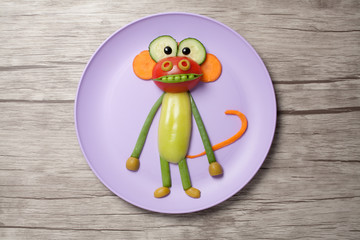Ape made of vegetables on plate and board