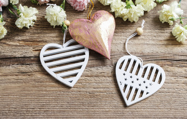 Hearts and carnation flowers on wooden background.