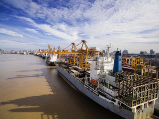 Aerial View Above the Bangkok Dockyard by the Chao Phraya River with Cargo Ships Waiting to be...