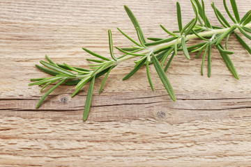 Rosemary (Rosmarinus officinalis) twig on wooden table
