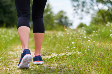 Girl is engaged in cardio runs through forest in sneakers, only legs are visible, legs and sneakers