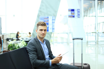 Businessman using digital tablet in airport departure lounge.