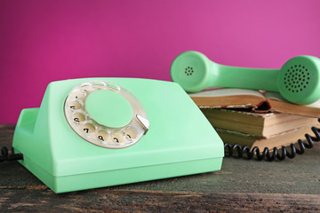 Green retro telephone with books on grey wooden table