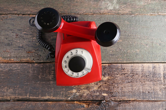 Red retro telephone on grey wooden table