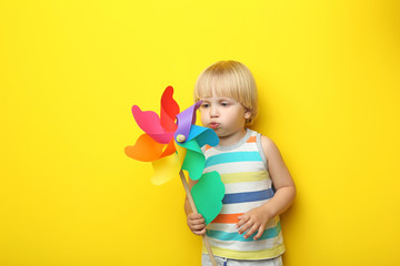 Portrait of little boy with rainbow whirligig on yellow background