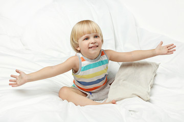 Little boy sitting in white bed