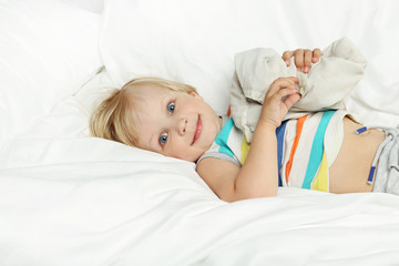 Obraz na płótnie Canvas Little boy lying in white bed