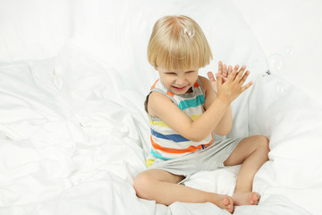 Fototapeta premium Little boy sitting in white bed