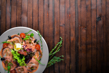 Carpaccio of fish, vegetables, cheese, spices, to Wooden background. Top view. Free space.