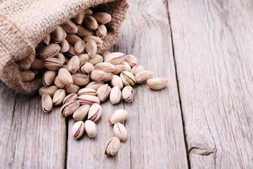 Pistachios in sackcloth bag on wooden table