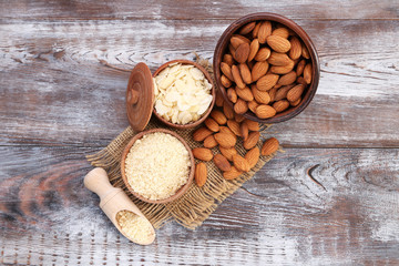 Almonds in bowl and scoop on wooden table