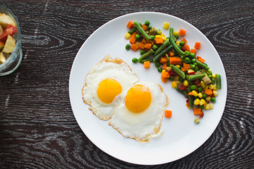 two fried eggs on the plate and vegetables
